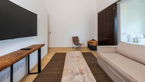 A modern living room with a flat-screen TV, a wooden bench, a sofa, a chair, and a large rug. - Penthouse Pacifico in Punta Mita (Punta de Mita)