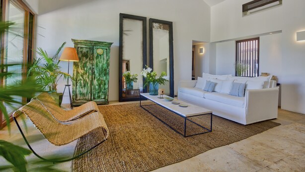 A living room with a white sofa, a woven chair, a coffee table, and a green cabinet. - Penthouse Pacifico in Punta Mita (Punta de Mita)