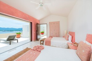 Ein Schlafzimmer mit zwei Betten, einem Balkon mit Stuhl und Meerblick.