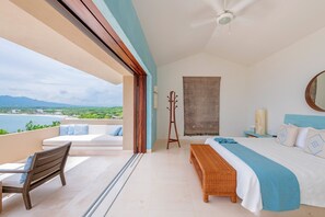 A bedroom with a bed, a bench, a chair, a bedside table, and a view of the outdoors. - Estate Ikal in Punta Mita (Punta de Mita)