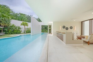 A modern pool area with a clear view of the pool, a bar area, and a seating area with a view of the greenery. - Estate Ikal in Punta Mita (Punta de Mita)