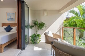 A balcony with a bed, a wicker chair, and a potted plant. - Condo Allegra in Punta Mita (Punta de Mita)