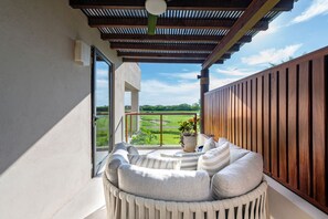 A balcony with a wooden pergola, a cushioned seating area, and a view of a golf course. - Condo Allegra in Punta Mita (Punta de Mita)