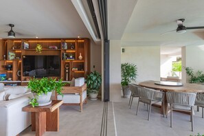 Ein modernes Wohnzimmer mit Kamin, Sofa, Couchtisch und Essbereich mit Stühlen.