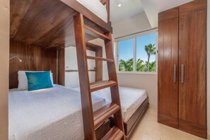A room with bunk beds, a wooden ladder, a wardrobe, and a window with a view of palm trees. - Condo Lago in Punta Mita (Punta de Mita)