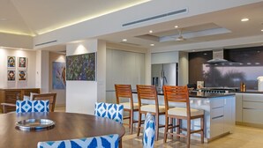 Eine moderne Küche mit einer zentralen Kochinsel, Essbereich mit gemusterten Stühlen und Deckenventilator.