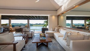 Ein modernes Wohnzimmer mit großem Fenster, Deckenventilator und Blick auf ein Gewässer.