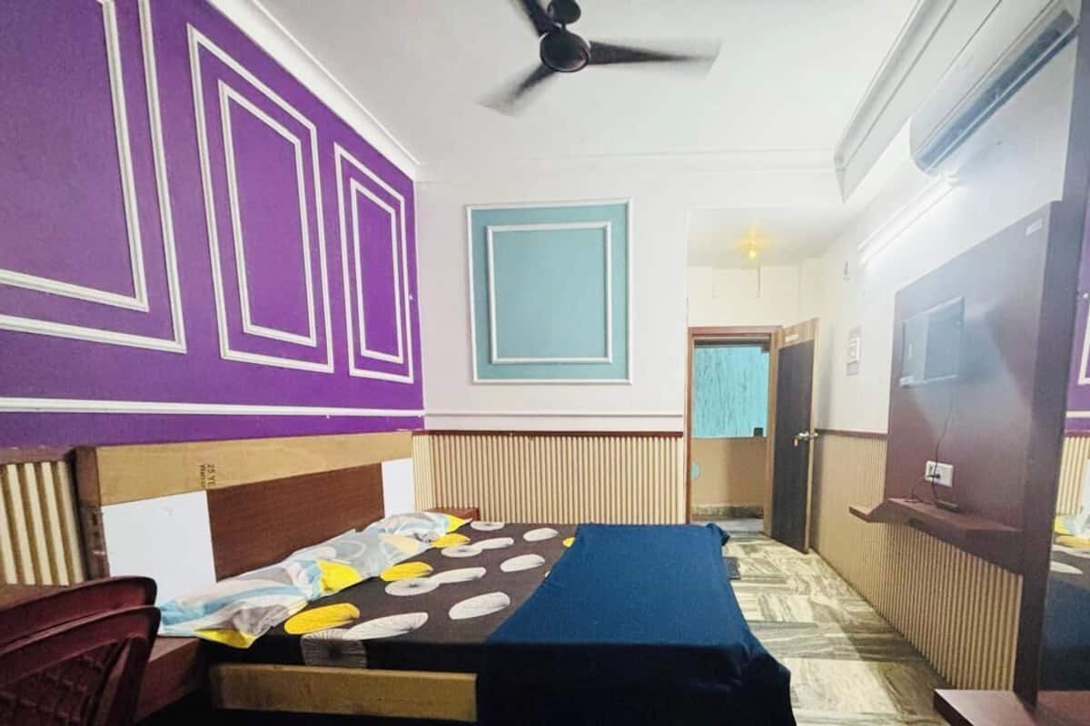 A room with a bed, a desk, a chair, and a ceiling fan.
