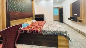 A bedroom with a bed, a chair, a wardrobe, and a small desk. - Hotel Sagar Bela OD (Puri)