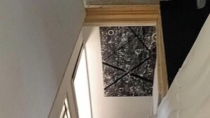 En trappa som leder upp till en liten plattform med en mönstrad matta och ett konstverk som hänger på väggen.