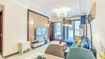 A modern living room with a sofa, dining table, TV, and decorative items.