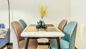 Een eethoek met een tafel, stoelen, een vaas met bloemen en een vloerlamp.
