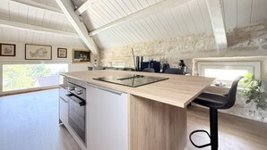 A kitchen with a wooden island, a built-in oven, and a stone wall. - N315 – Numana, new, fully equipped two-room apartment (Numana)