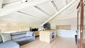 A modern loft-style living space with a kitchen, a built-in sofa, and a stone wall. - N315 – Numana, new, fully equipped two-room apartment (Numana)