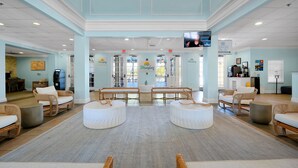 A spacious lobby with wicker furniture, a central seating area, and a television mounted on the wall. - Bahama Bay Resort - Ground Floor (Davenport)