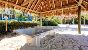A ping pong table under a wooden pavilion with a thatched roof, surrounded by sand and greenery. - Bahama Bay Resort - Ground Floor (Davenport)