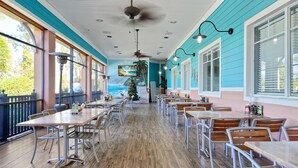 A restaurant with wooden tables and chairs, a ceiling fan, and large windows with a view of the outdoors. - Bahama Bay Resort - Ground Floor (Davenport)