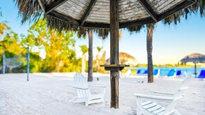 A beach with white lounge chairs, a wooden post, and a thatched umbrella. - Bahama Bay Resort Penthouse w Lake View 15209 (Davenport)