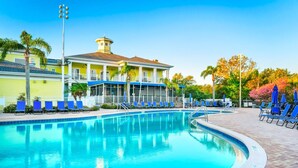 A swimming pool with blue lounge chairs, a covered area, and a building with a yellow facade. - Bahama Bay Resort Penthouse w Lake View 15209 (Davenport)