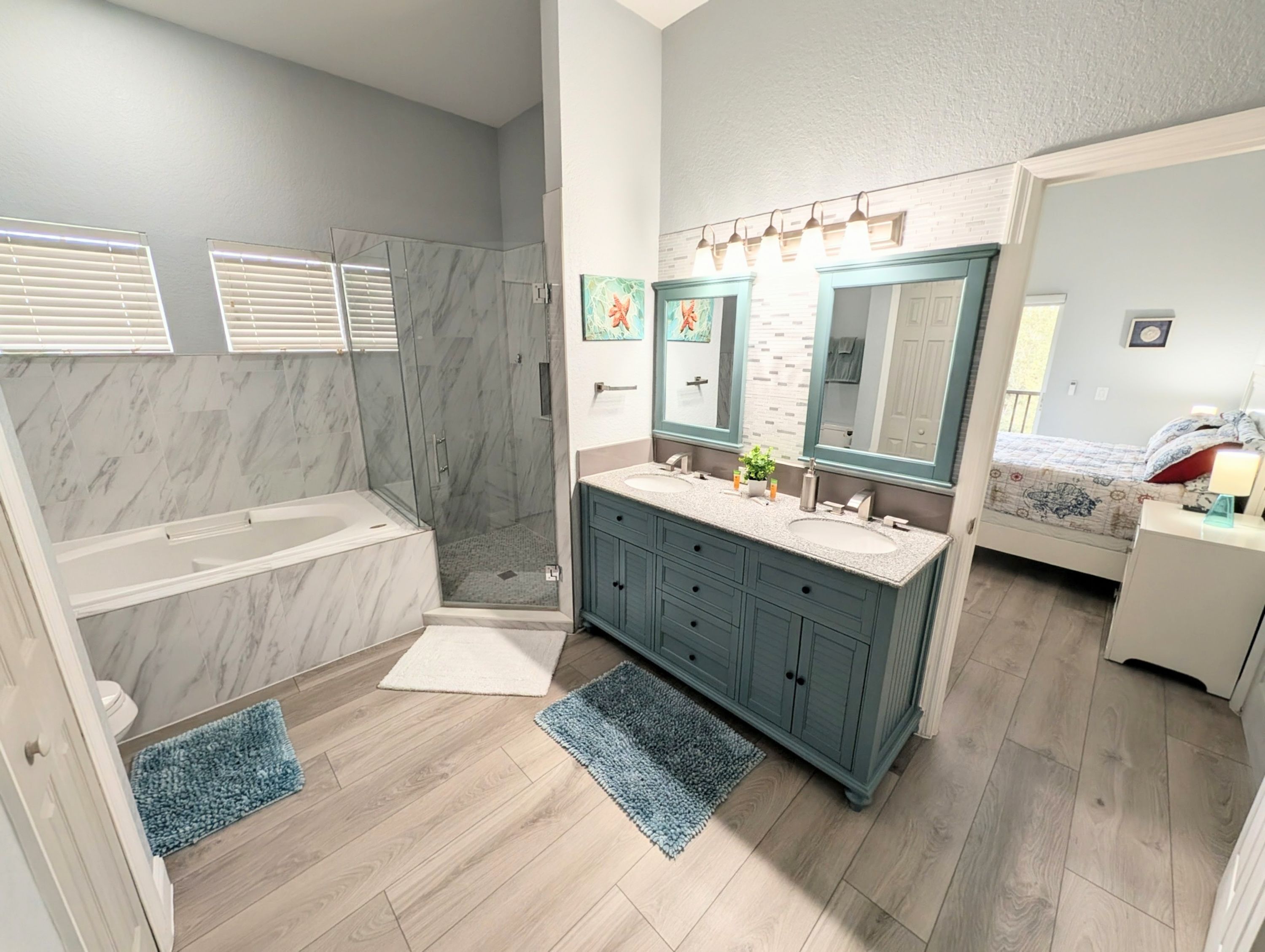 Un baño moderno con ducha, dos lavamanos, tocador y un espejo grande.