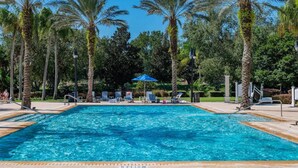 A swimming pool surrounded by palm trees and lounge chairs. - Luxury Seven Eagles Townhome in Reunion Resort (Kissimmee)