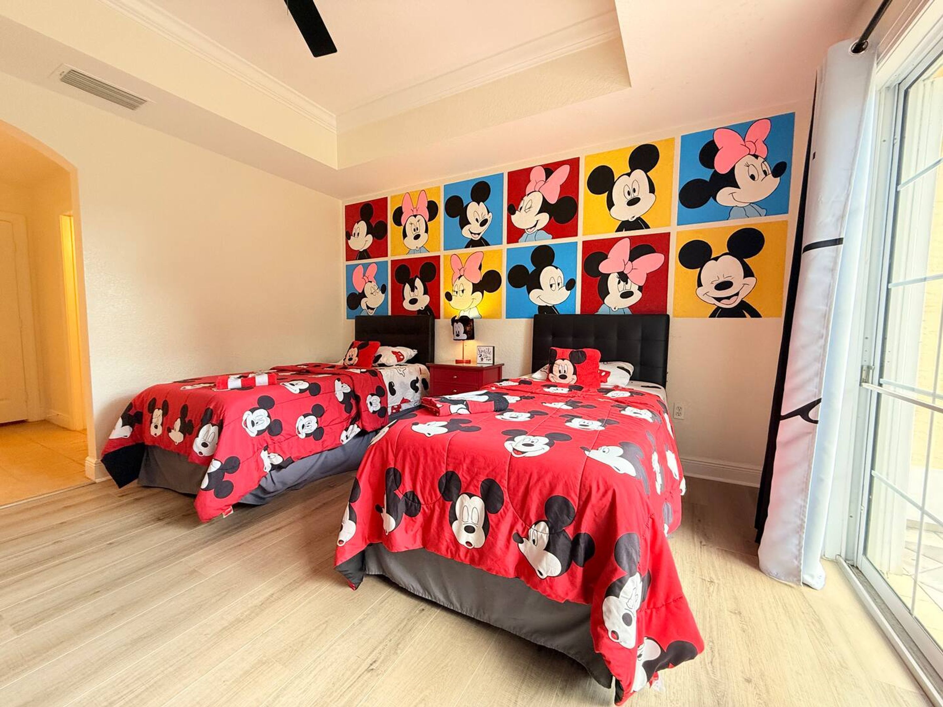 Ein Hotelzimmer mit zwei Betten, jeweils mit Micky Maus-Betwäsche bezogen.