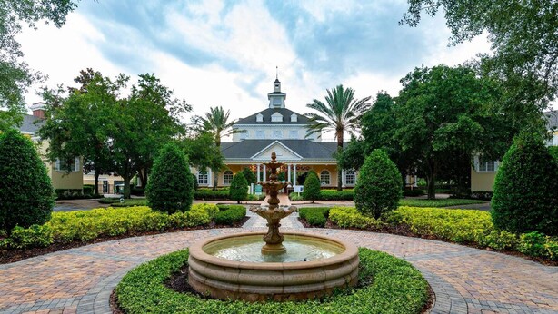 A courtyard with a central fountain, surrounded by well-manicured hedges and a brick pathway. - Luxury Seven Eagles Townhome in Reunion Resort (Kissimmee)