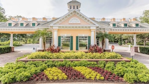 A building with a central entrance, a tower, and a covered walkway. - Luxury Seven Eagles Townhome in Reunion Resort (Kissimmee)