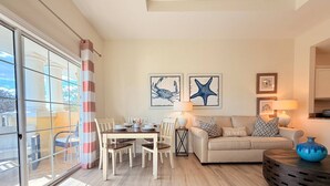 A living room with a dining table, sofa, and a large window with curtains. - Luxury Seven Eagles Townhome in Reunion Resort (Kissimmee)