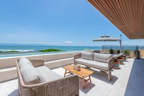 A rooftop terrace with wicker furniture, a wooden table, and potted plants. - Rooftop Oasis in Punta Mita (Punta de Mita)