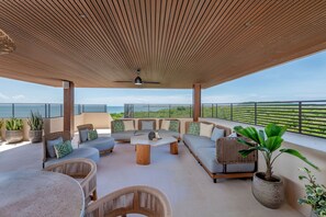 An outdoor seating area with wicker furniture, a central coffee table, and potted plants. - Rooftop Oasis in Punta Mita (Punta de Mita)