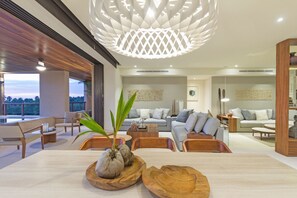A modern living room with a dining area, wooden furniture, and a unique ceiling light fixture. - Condo Ceres in Punta Mita (Punta de Mita)