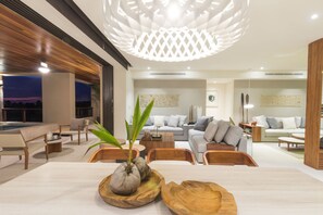 A modern living room with a dining area, a pool, and a large ceiling light fixture. - Condo Ceres in Punta Mita (Punta de Mita)