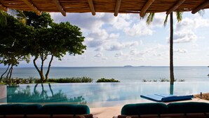 An infinity pool with a view of the ocean, lounge chairs, and a thatched roof structure. - Estate Venado in Punta Mita (Punta de Mita)