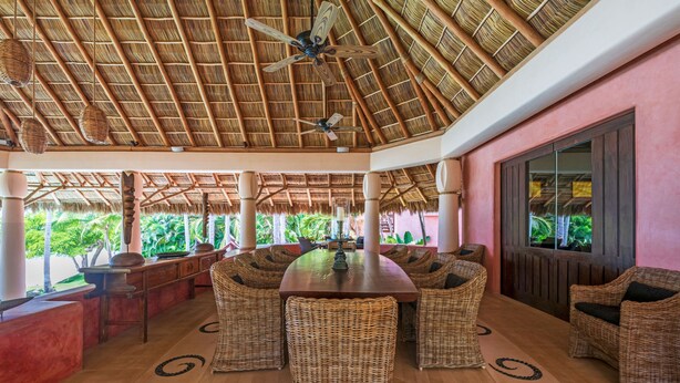 A covered outdoor dining area with wicker furniture, a central table, and a ceiling fan. - Estate Venado in Punta Mita (Punta de Mita)