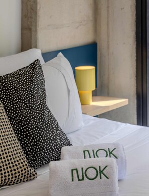 A neatly made bed with white linens, a polka dot pillow, a plain pillow, and a yellow bedside lamp. - NOK Comfortable 1BR Apartment in Chico Norte (Bogotá)