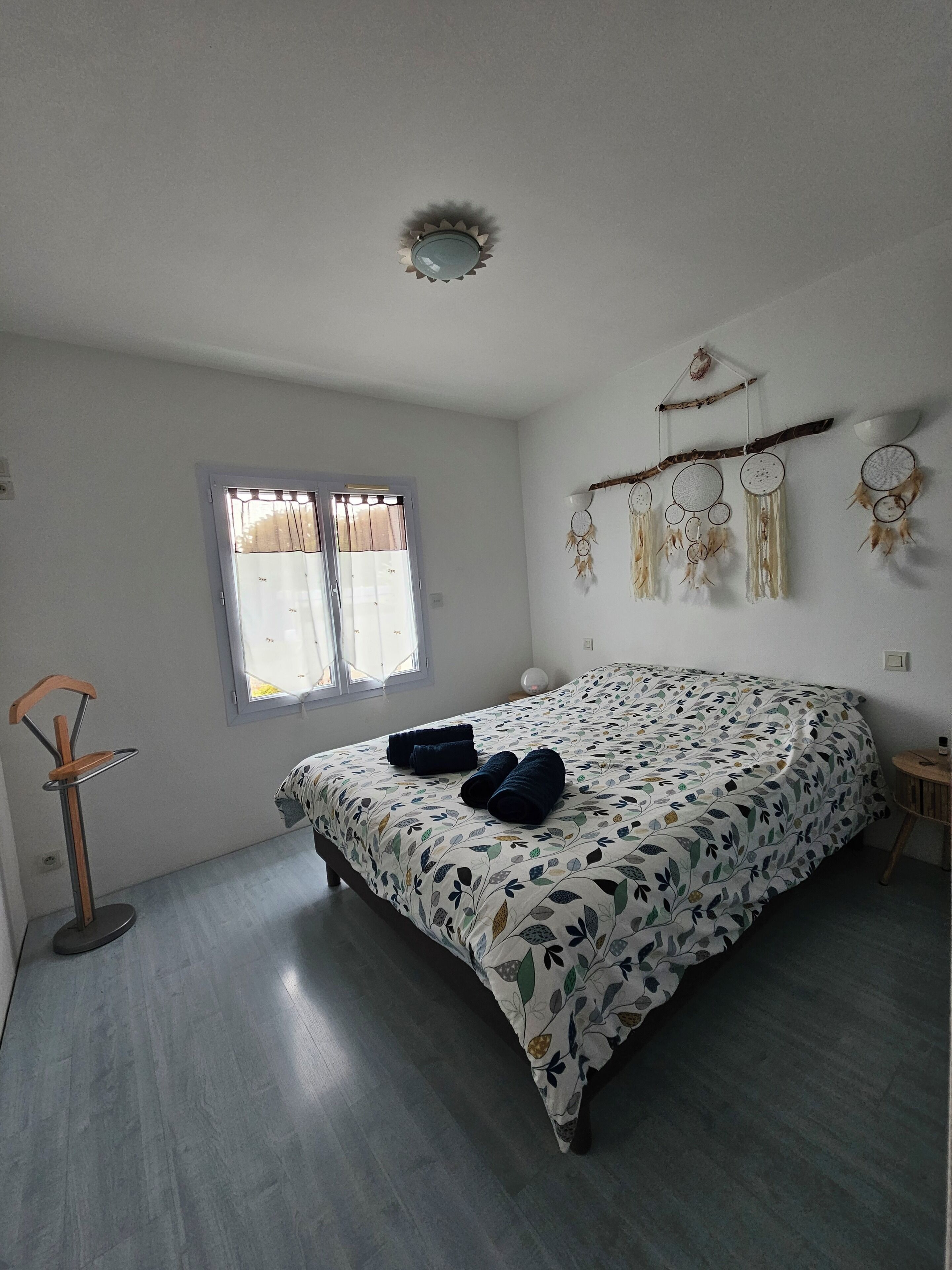 A bedroom with a bed, a standing lamp, a window, and wall decorations.