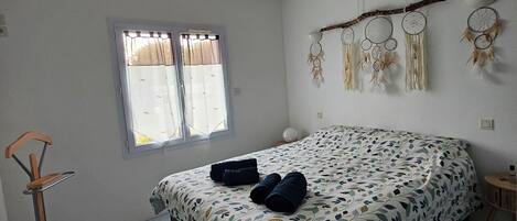 Un dormitorio con cama, lámpara de pie, ventana y adornos en la pared.