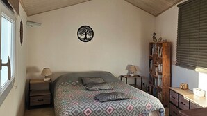 A bedroom with a bed, a nightstand, a bookshelf, and a window. - Welcome to Les Renaudelles (Angles)