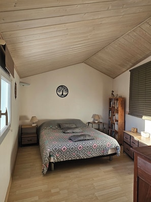 A bedroom with a bed, a nightstand, a bookshelf, and a window. - Welcome to Les Renaudelles (Angles)
