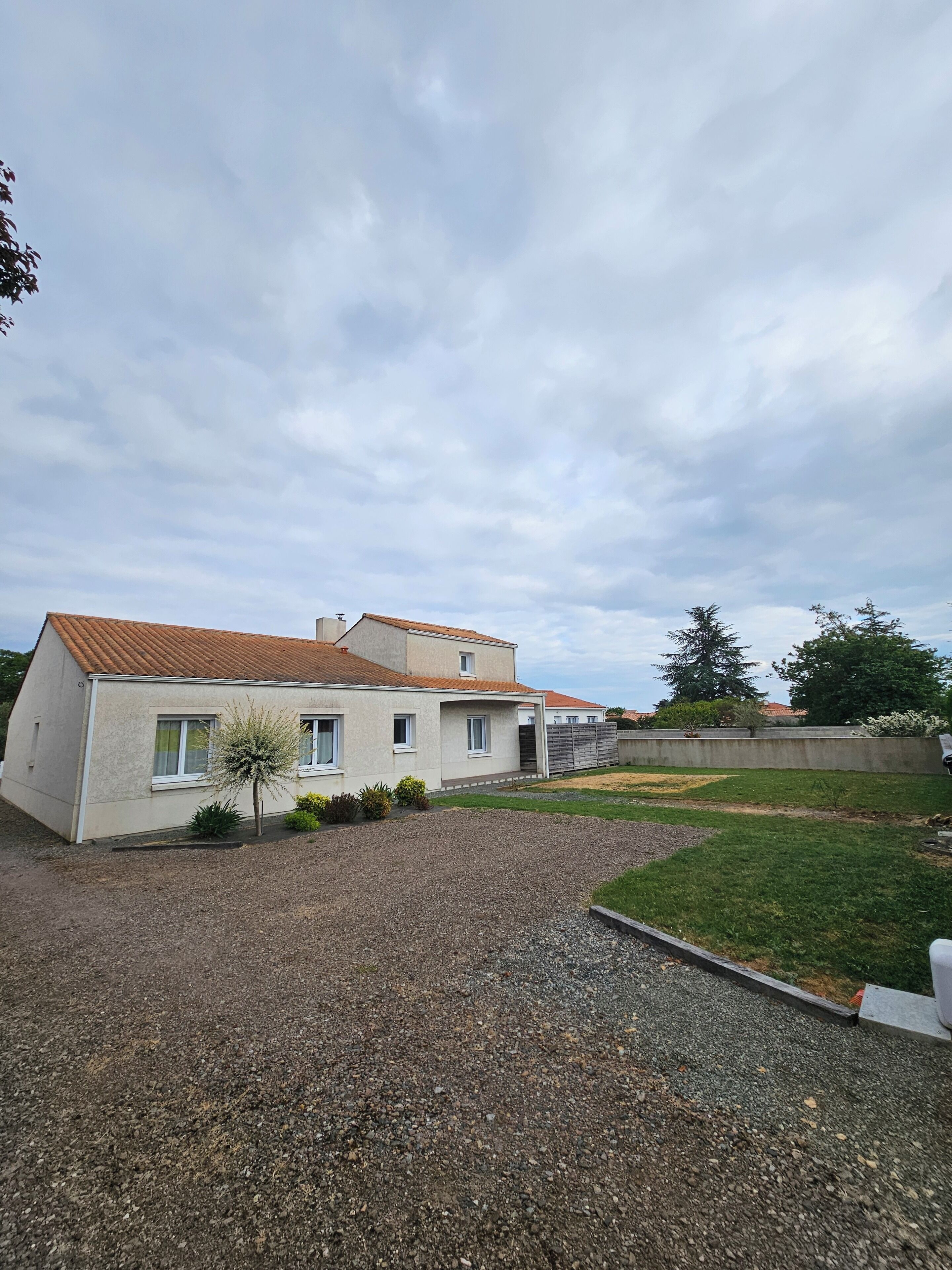 A two-story house with a gravel driveway and a small lawn.