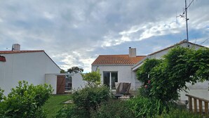A residential area with white houses, a red-tiled roof, and a garden with green shrubs. - Welcome to Les Renaudelles (Angles)