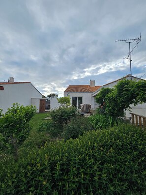 A residential area with white houses, a red-tiled roof, and a garden with green shrubs. - Welcome to Les Renaudelles (Angles)