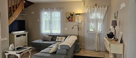 A living room with a sofa, a television, a lamp, and a staircase.