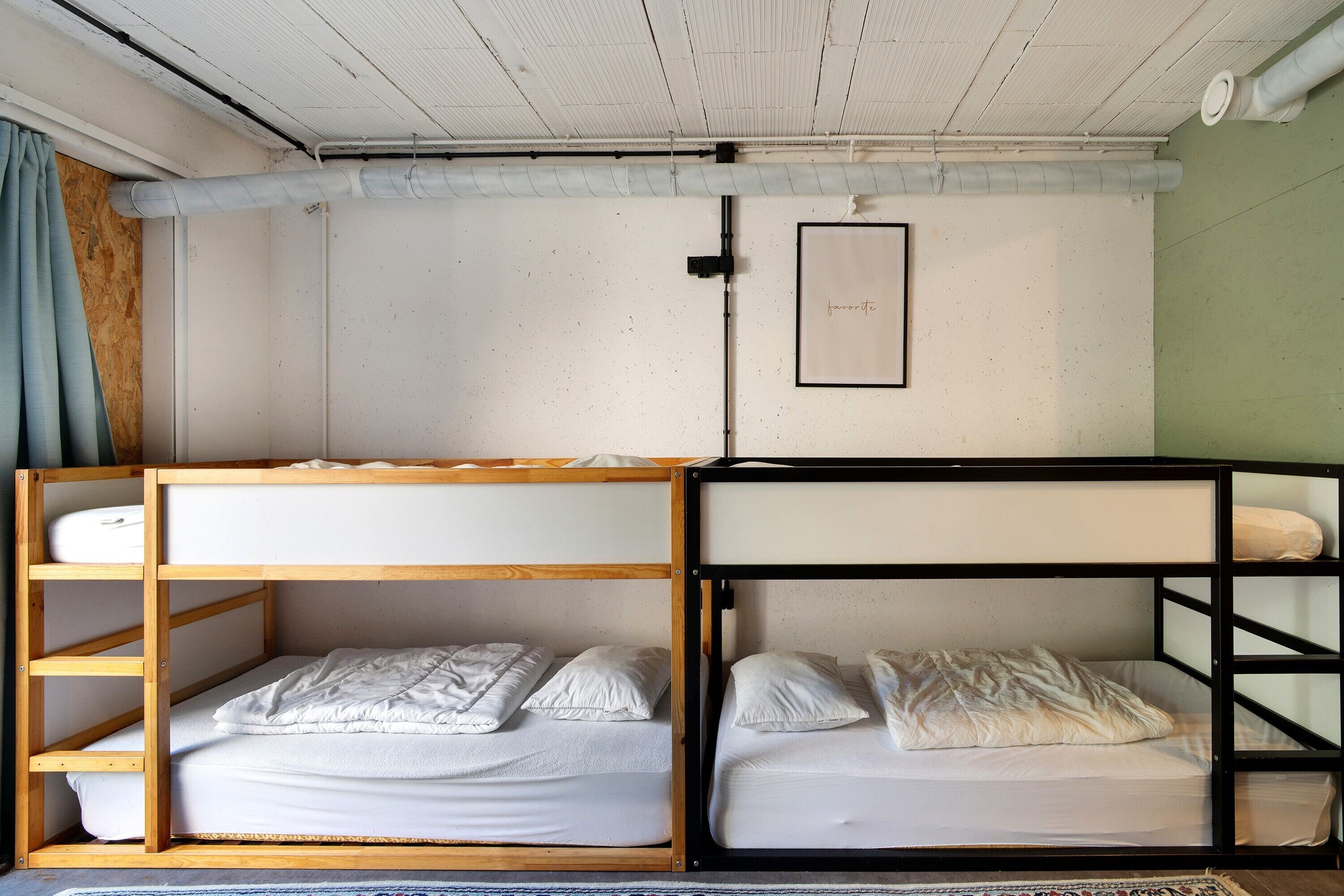 Habitación con literas de madera, un colchón blanco y una estructura de cama alta negra.