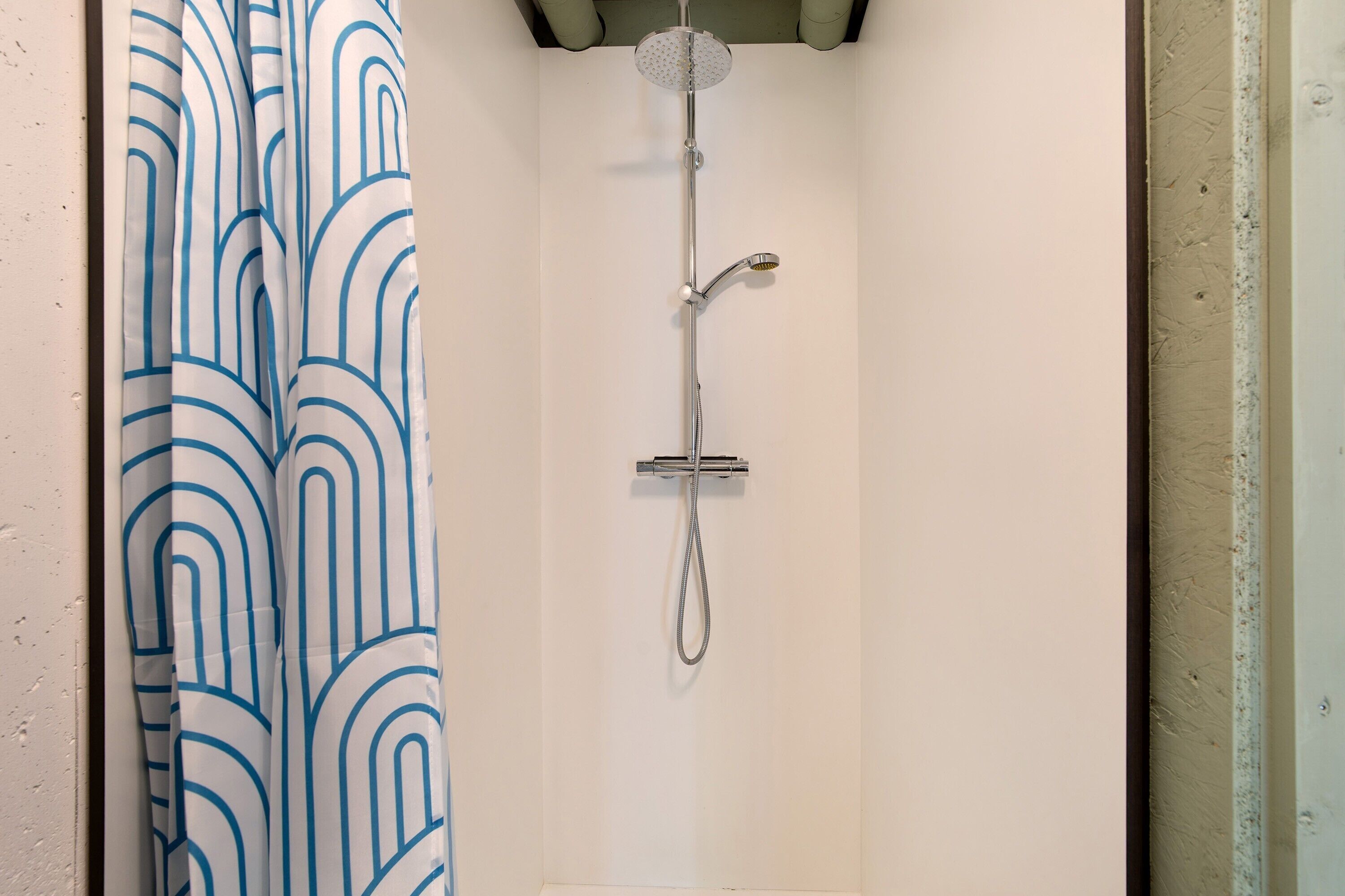 A shower with a handheld showerhead and a wall-mounted faucet.
