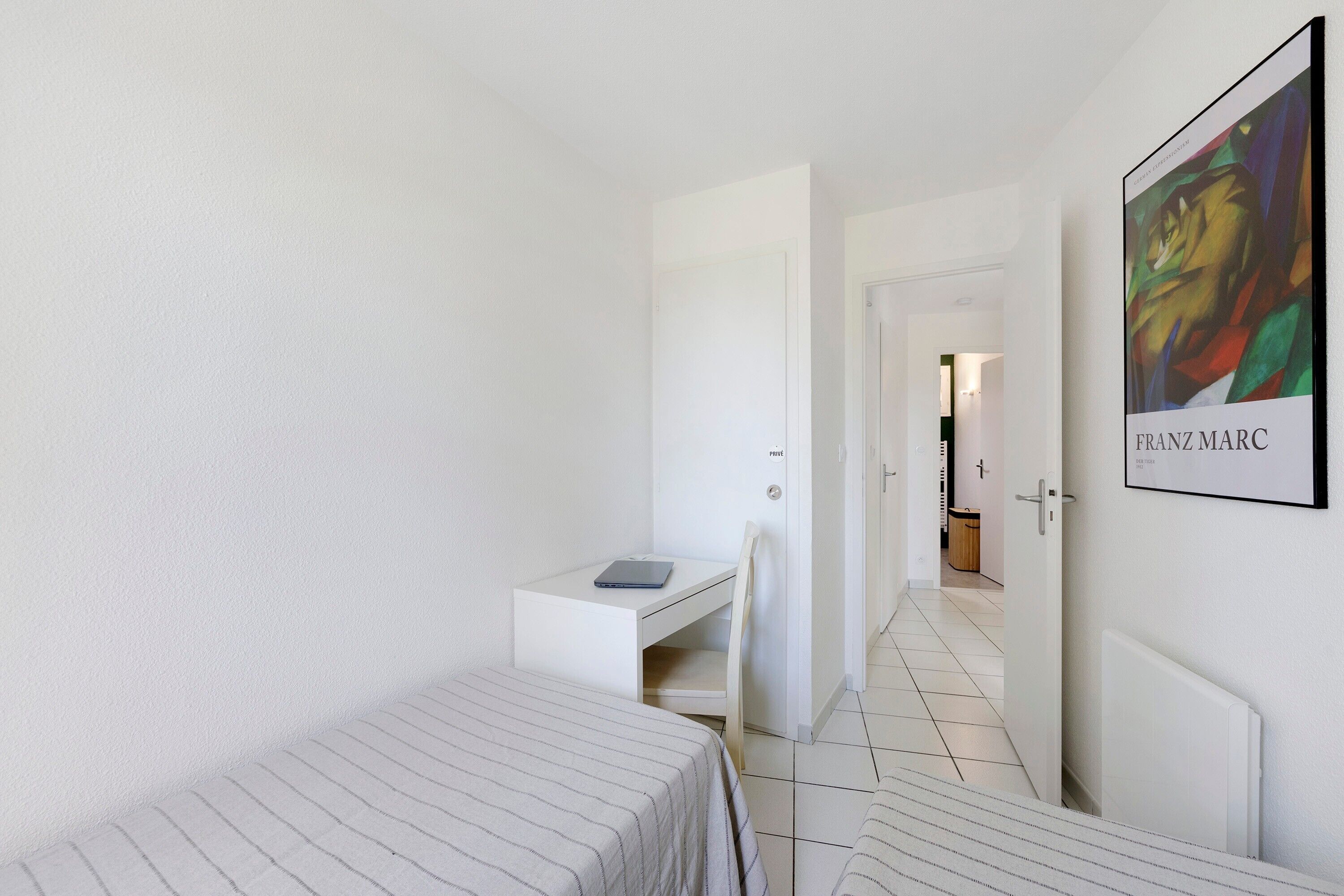 Une chambre d’hôtel avec un lit, un bureau, une chaise et un tableau encadré au mur.