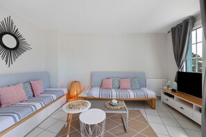A modern living room with two sofas, a coffee table, a TV, and a decorative wall piece. - La Terrasse du Golf Bourgenay – Spacious Apartment with Large South-Facing Terrace (Talmont-Saint-Hilaire)