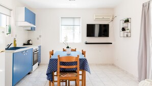 Una cocina moderna con armarios azules, una mesa de comedor con mantel a cuadros y un televisor montado en la pared.
