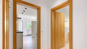 A hallway with wooden doors leading to a kitchen and a bathroom.